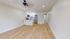Modern open-plan living area with elegant wood flooring, featuring a sleek kitchen with stainless steel appliances and minimalist white cabinetry.