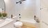 Bright, modern bathroom with sleek white tiles, elegant fixtures, and fresh floral accents.