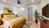 Inviting and stylish bedroom with warm tones, featuring a comfortable bed, modern artwork, vibrant plants, and sleek wooden furniture.