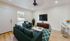 Modern living room with plush teal sofas, vibrant patterned rug, and a sleek wall-mounted TV, creating a cozy and inviting atmosphere.