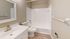 Chic and modern bathroom featuring a sleek vanity, pristine bathtub, and elegant wood flooring for a luxurious touch.