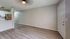 Elegant apartment interior with modern gray walls, sleek ceiling fan, inviting laminate wood flooring, and a stylish open kitchen with stainless steel appliances.