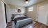 Charming bedroom with a cozy queen-sized bed, elegant artwork, and warm lighting, complemented by rich wooden flooring for a welcoming ambiance.