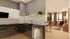 Modern kitchen with sleek cabinetry opens into a cozy living room adorned with stylish decor and natural light.