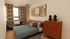 Elegantly designed bedroom featuring geometric art, stylish furniture, and modern decor with warm tones and natural light.