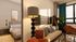 Modern apartment interior with cozy bedroom and stylish living area featuring elegant decor, abstract art, and warm natural light.