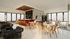Elegant open-concept lounge featuring a chic bar with modern stools, cozy seating area with plush armchairs, and large windows offering abundant natural light.