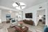 Modern apartment living room with elegant decor, featuring a cozy seating area, large TV, wooden floors, and a glimpse into a stylish bedroom.
