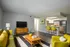 Bright and contemporary living area featuring stylish yellow accents, sleek wood furniture, and an open kitchen with modern appliances.