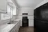 Modern kitchen with sleek black appliances, polished countertops, and bright cabinetry offering ample storage and charm.