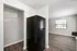 Modern apartment corner featuring a sleek black refrigerator, stylish hardwood flooring, and an inviting natural light-filled space with large windows.
