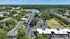 Scenic aerial view of a charming apartment complex surrounded by lush greenery and serene water views, showcasing spacious parking areas and well-maintained buildings.