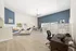 Bright and spacious open-concept living area with modern decor, featuring elegant blue accent wall, cozy seating, and stylish partition for workspace.