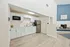 Modern kitchen with sleek white cabinetry, stainless steel appliances, and elegant wood flooring opening to a stylish living area with a cozy fireplace.