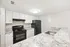 Modern kitchen with sleek black appliances, white cabinetry, and elegant granite countertops.