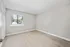 Bright and spacious bedroom with modern laminate flooring, large window with a view, and clean white walls.