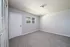 Bright and spacious empty bedroom with soft carpet flooring and a window letting in natural light.