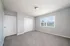 Bright and spacious bedroom with plush carpeting, ample closet space, and a large window offering serene garden views.