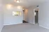 Bright and inviting living room with soft carpet flooring, modern lighting, and a convenient pass-through to the kitchen, offering an open and airy layout.