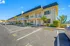 Charming two-story apartment building with lush palm trees and ample parking, bathed in bright natural light.