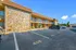 Inviting two-story apartment complex with stone facade, ample parking, and lush greenery under a clear blue sky.