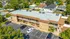 Aerial view of a charming two-story apartment building with ample parking and lush green surroundings.