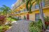 Charming two-story apartment community with vibrant garden landscaping and palm trees, set under a clear blue sky.