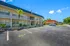 Bright and welcoming apartment complex with lush landscaping and ample parking under a clear blue sky.