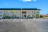 Charming two-story apartment building with lush landscaping and convenient parking, under a clear blue sky.