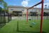 Charming community playground with vibrant red swings set against a backdrop of well-maintained townhouses, ideal for family-friendly living.