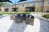 Chic outdoor patio featuring a stylish wicker sofa with striped cushions and a modern glass coffee table, set against charming townhouse exteriors.