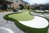 Beautiful apartment courtyard featuring a modern mini-golf green surrounded by manicured grass and stylish landscaping.