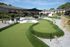 Charming apartment complex courtyard featuring a mini-golf course, lush landscaping, and outdoor seating under stylish canopies.