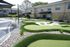Charming apartment complex featuring a beautifully landscaped mini-golf course surrounded by lush greenery and pebbled pathways.