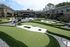 Luxurious apartment complex featuring an expertly designed mini-golf course surrounded by lush greenery and modern outdoor seating areas.