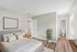 Bright and inviting bedroom with chic decor, featuring a comfortable bed, elegant side table, and abundant natural light with a view into an ensuite bathroom.