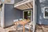 Charming outdoor patio with stylish wooden dining set and modern blue siding, perfect for relaxing and entertaining.