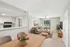 Inviting open-plan living space with modern kitchen and cozy seating area, featuring abundant natural light from large windows.