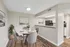 Chic dining area with elegant table setting beside a sleek, modern kitchen featuring stainless steel appliances and stylish artwork.