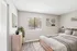 Bright, stylish bedroom with modern decor, featuring large window, cozy bedding, and a sleek dresser with potted plants.