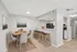 Modern dining area with a stylish table set for four, connected to a chic kitchen with sleek bar seating and contemporary lighting.