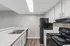 Modern kitchen with sleek appliances, white cabinetry, and stylish countertops, enhanced by natural light from the ceiling skylight.