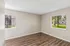 Bright room with stylish wood floors and large windows offering scenic views of lush greenery.