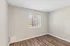 Bright and airy room with elegant neutral walls, rich hardwood flooring, and a window offering serene outdoor views.