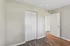 Bright bedroom with stylish white closet doors and modern flooring, showcasing ample natural light and contemporary design.