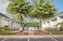 Inviting apartment complex entrance with lush palm trees and a gated path, offering a glimpse of vibrant, spacious living.