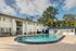Inviting apartment complex showcasing a sparkling swimming pool, surrounded by lush greenery and chic outdoor seating.
