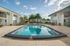 Vibrant apartment complex showcasing a sparkling outdoor pool surrounded by palm trees and inviting balconies.