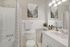 Bright and modern bathroom featuring a sleek white vanity, elegant wall art, and a chic shower curtain, perfect for a stylish living environment.