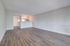 Modern open-concept living space with sleek wood flooring, neutral walls, and a cozy kitchen area.
